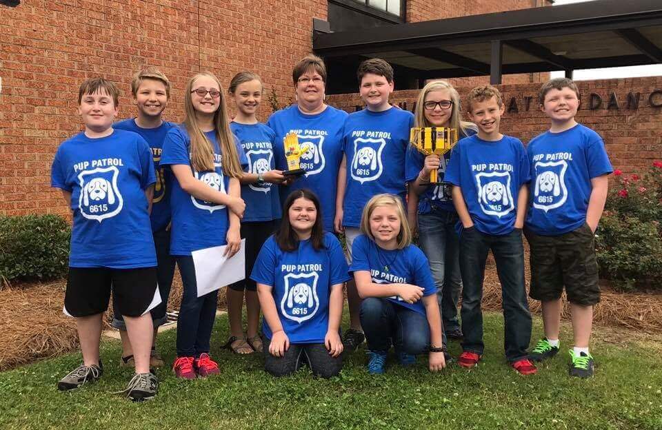 Students and their teacher stand together in matching blue "pup patrol" shirts