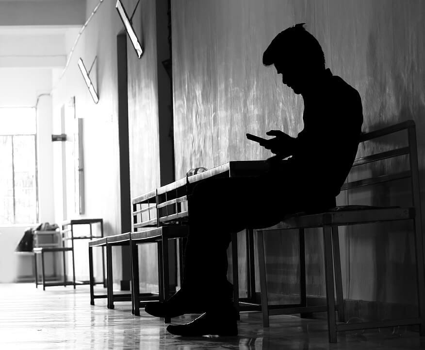 Man on phone in the shadows looking sad