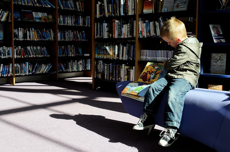 Child reading a book in a library