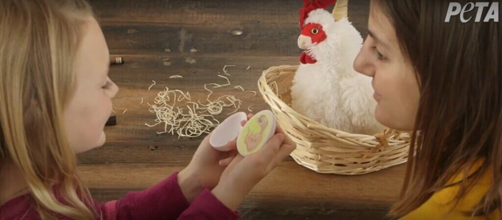 Child opens a plastic egg with an image of a chick inside