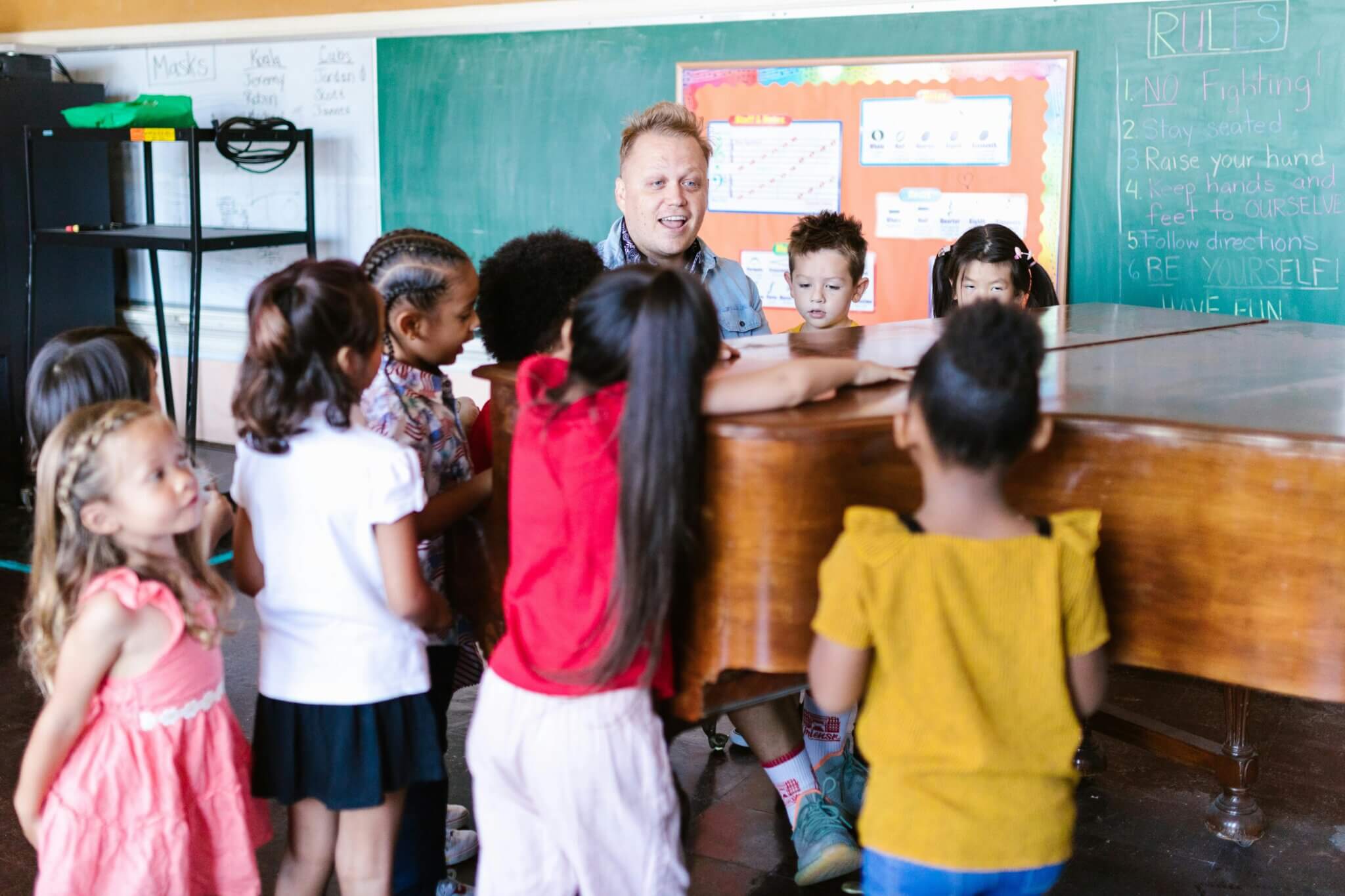 Group of Children Standing Near a Teacher Playing Piano