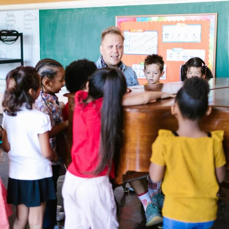 Group of Children Standing Near a Teacher Playing Piano
