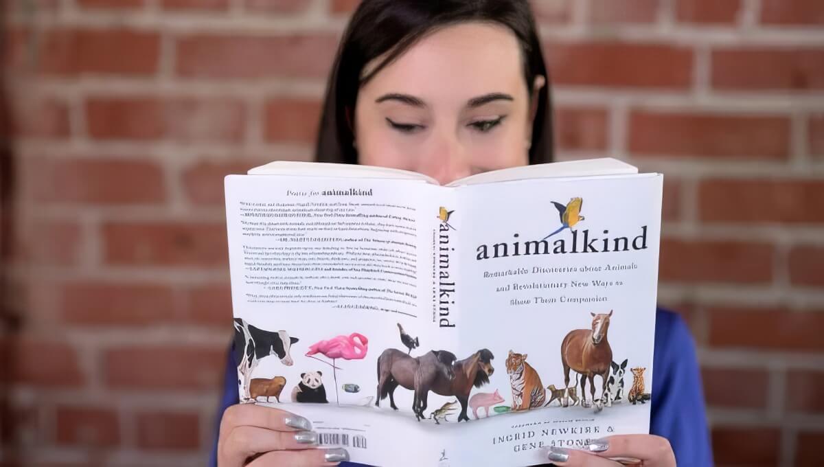 Person reading the book, 'Animalkind' by Ingrid Newkirk
