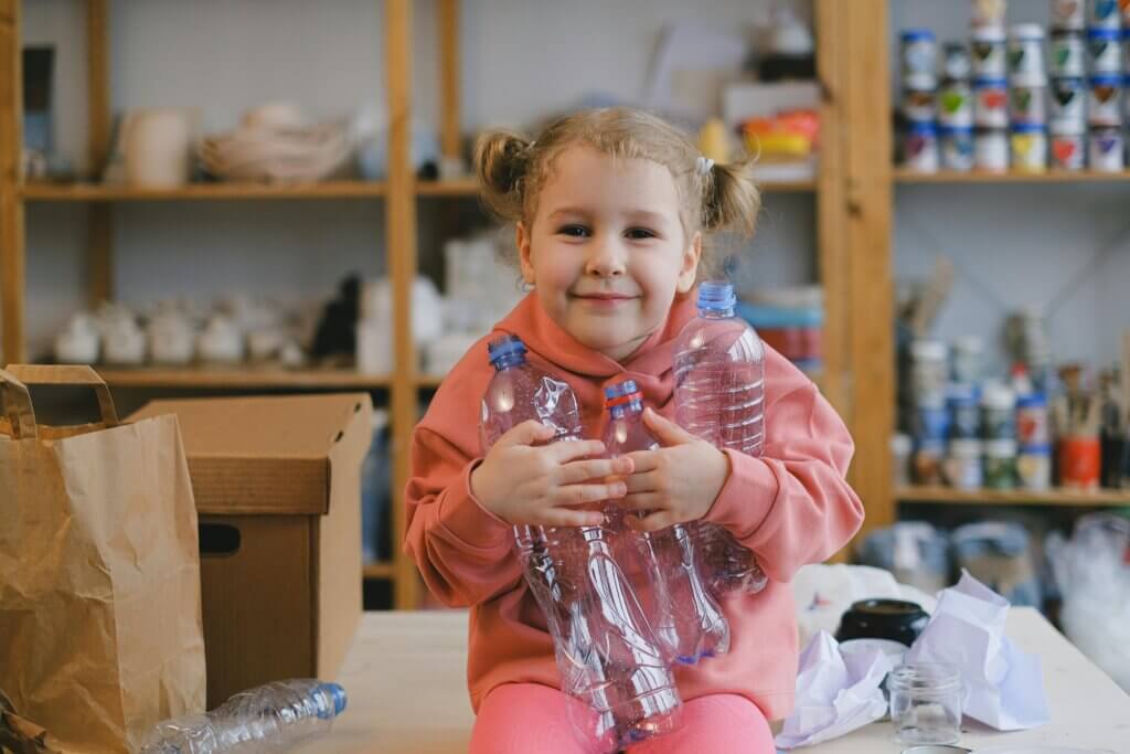 Girl in Pink Sweater Holding Plastic Bottles