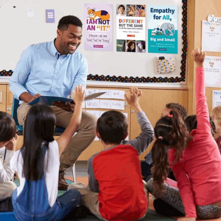 A teacher is reading to children and their hands are raised.