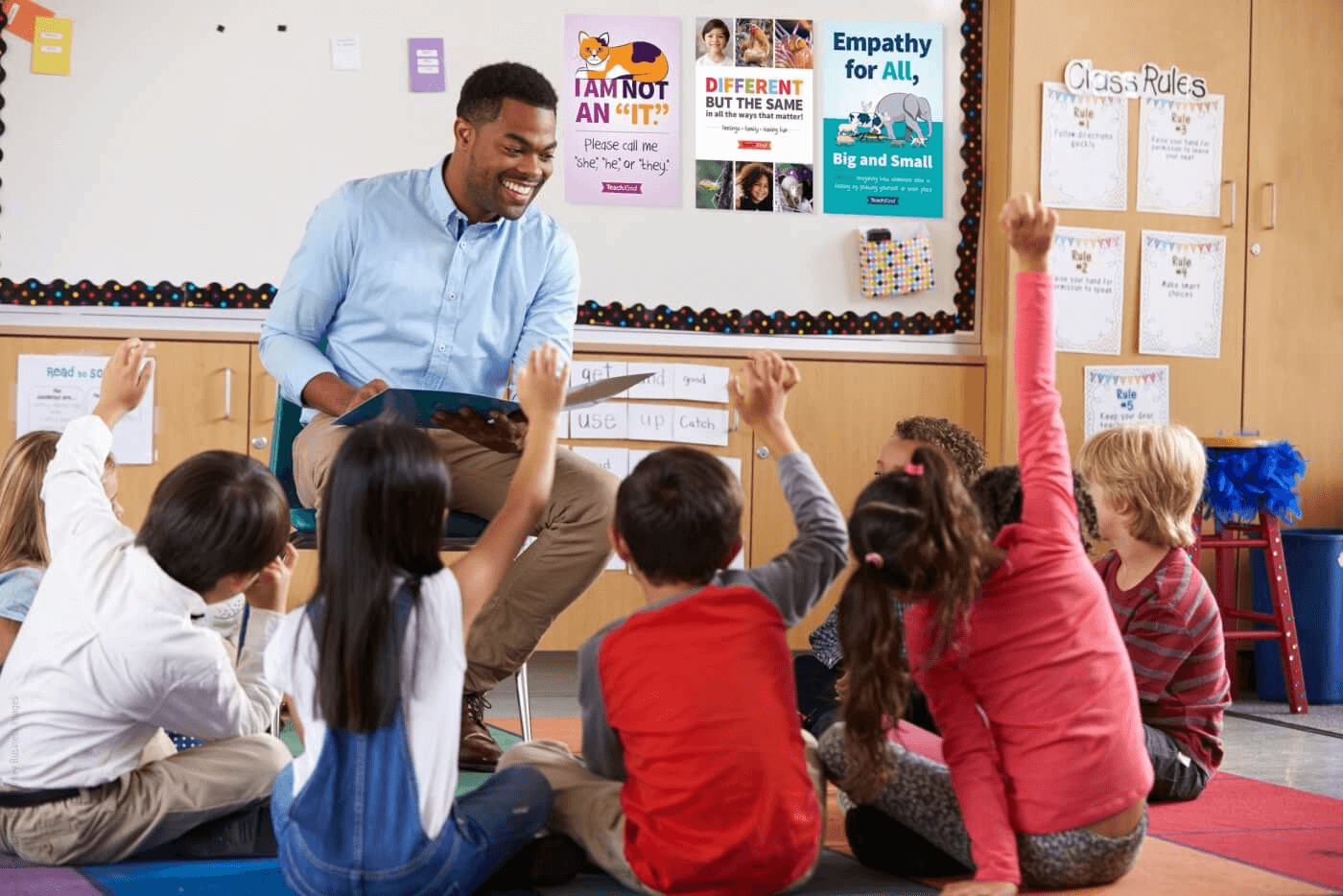 A teacher is reading to children and their hands are raised.