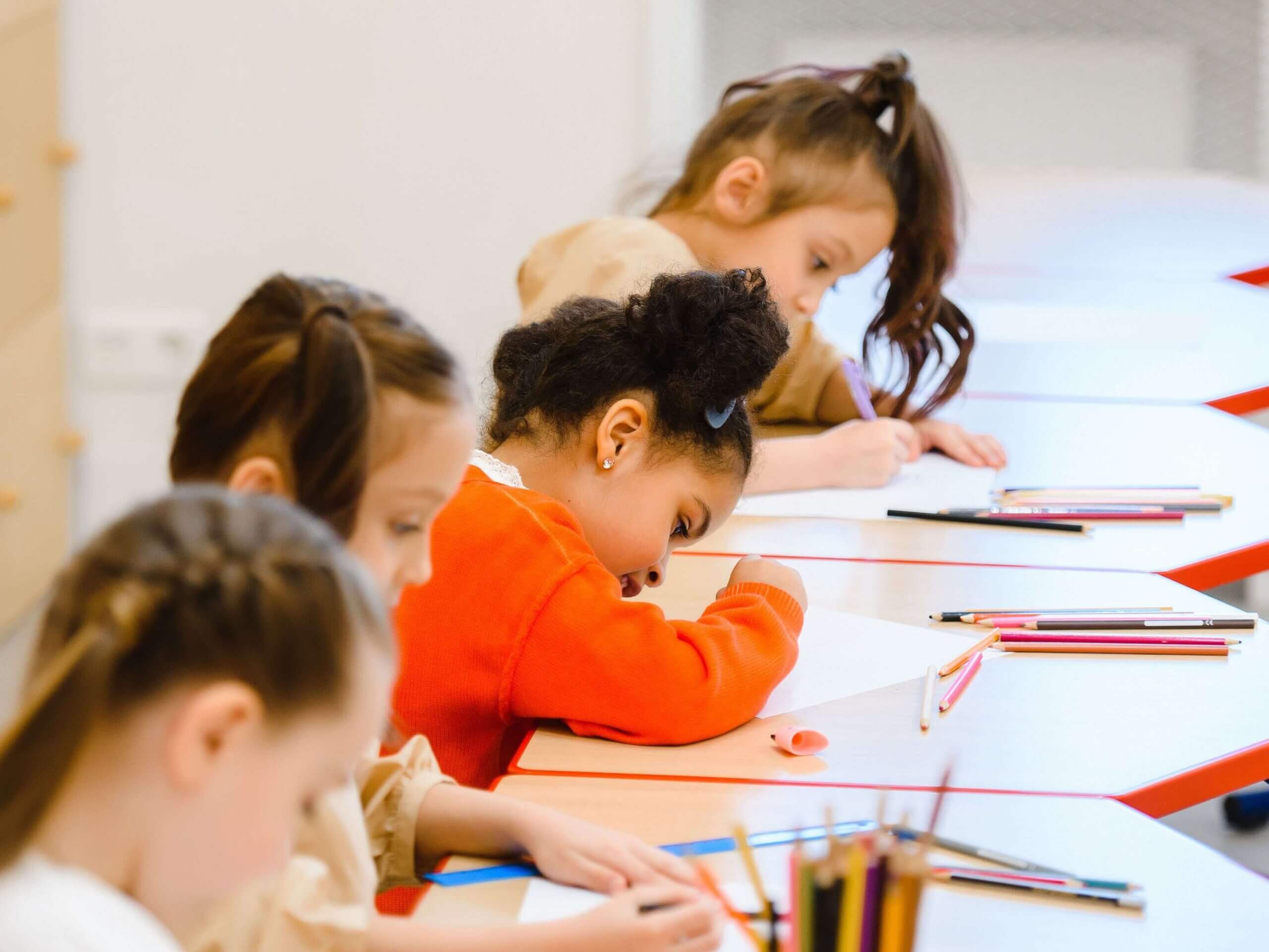 Group of children focused on schoolwork in a bright classroom setting.