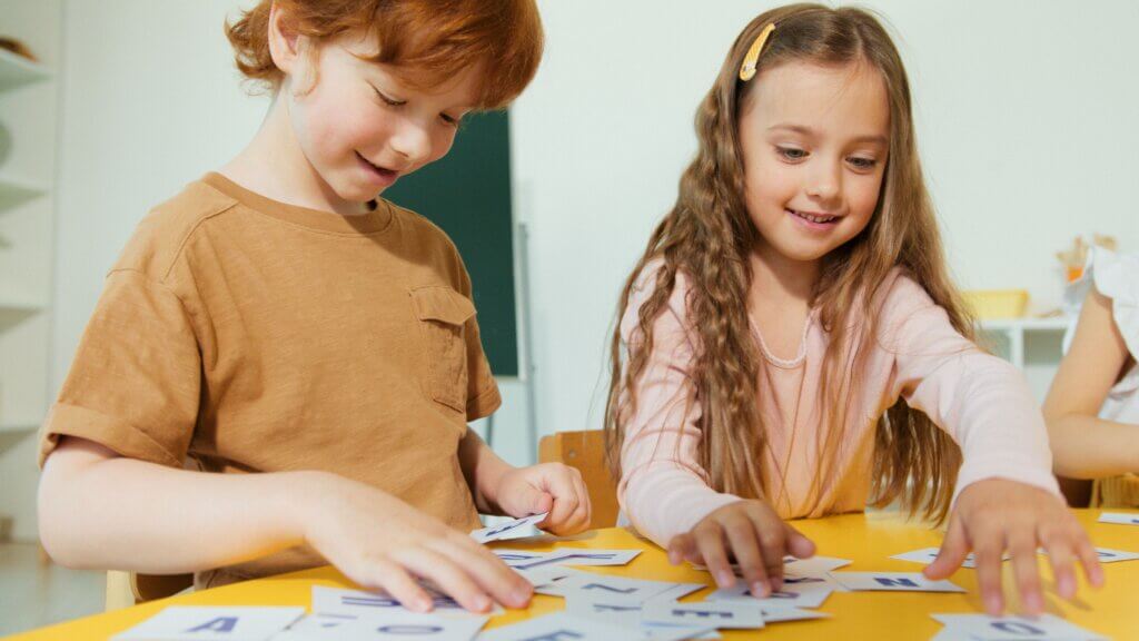 Happy children engaged in learning with alphabet cards.