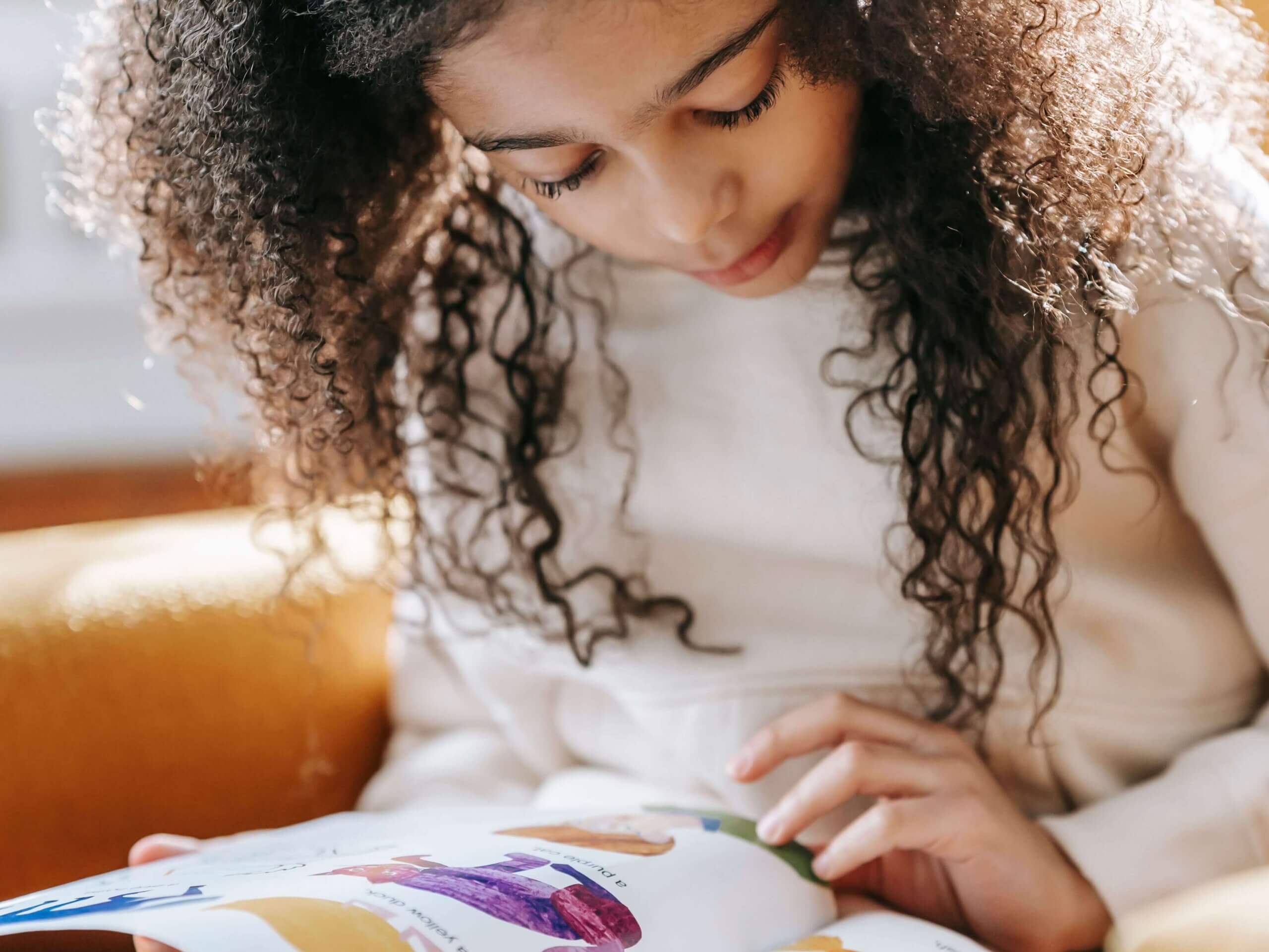 An elementary student reads a colorful book in a classroom.