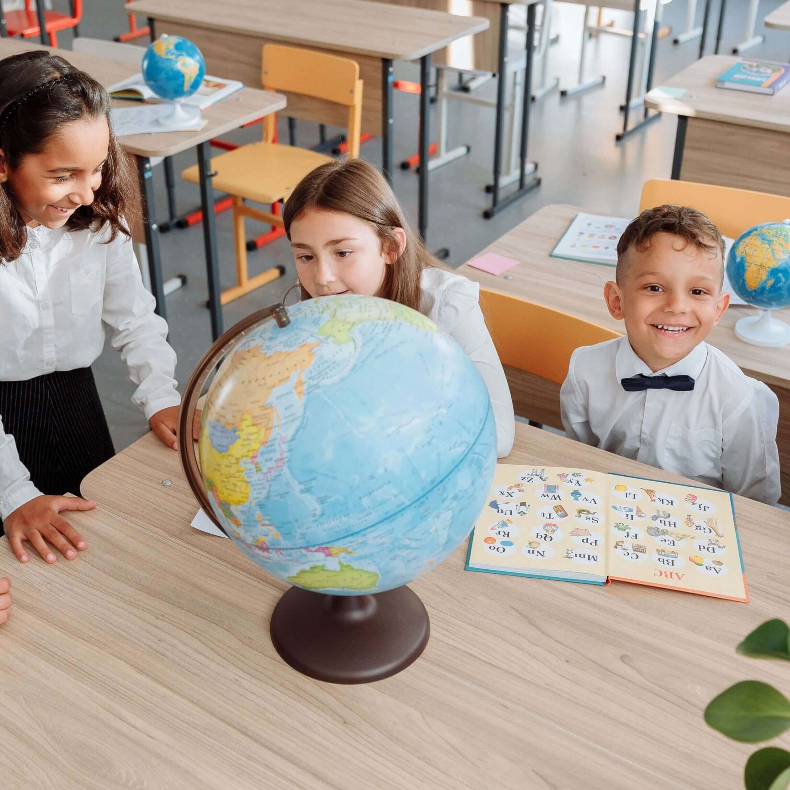 Group of children learning about geography using a globe in a bright classroom setting